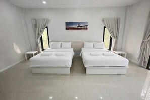 A modern hotel room with two single beds, a large window with curtains, a small bedside table, and a wall-mounted picture.