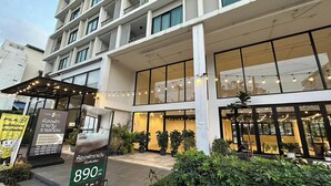 Un hotel moderno con una entrada amplia, varios pisos y un área exterior cubierta con guirnaldas de luces.