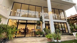 Un edificio moderno con amplios ventanales, asientos exteriores y plantas en macetas.