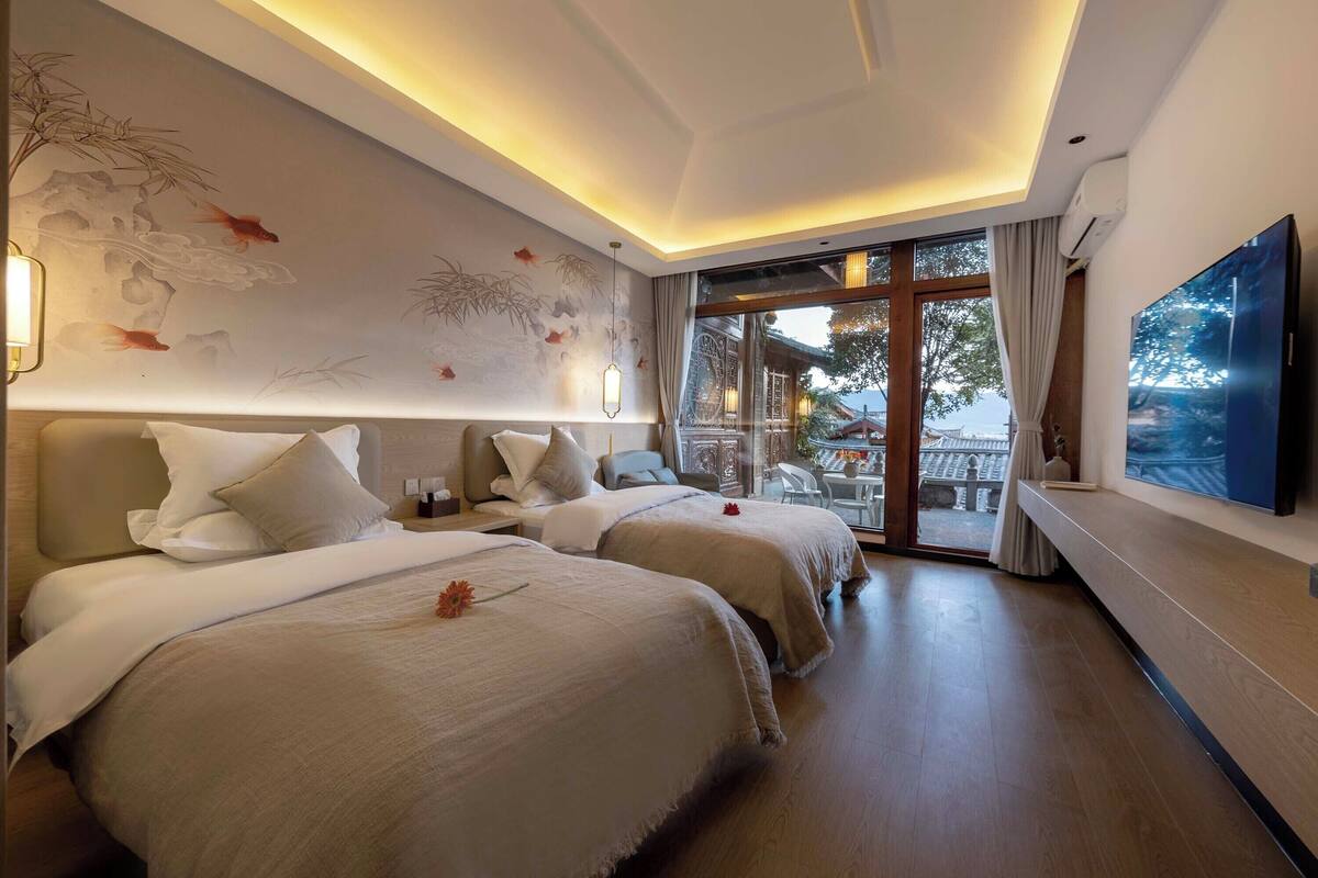 A hotel room with two beds, a large TV, and a view of the outside.