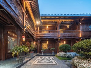 A traditional wooden building with intricate carvings, a balcony, and potted plants. - Yiyun Tingju Viewing Ancient Courtyard (Lijiang)
