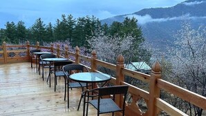 A wooden deck with outdoor seating and a view of a mountainous landscape. - Haven Resort and Spa (Paro)