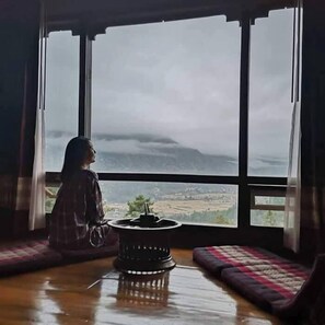 Una habitación con ventanas amplias, una mesa central y vistas a un paisaje.