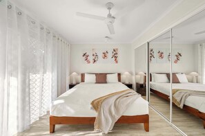Een slaapkamer met een groot bed, een plafondventilator en kunst aan de muur.