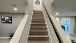 Een moderne trap met een minimalistisch ontwerp, leidend naar een plateau met een ronde lamp.