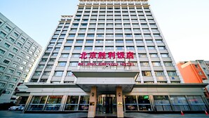 A multi-story hotel building with a prominent sign reading "Beijing Shengli Hotel".
