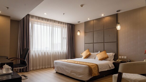 A hotel room with a large bed, a desk with a telephone, and a chair.