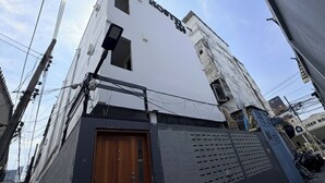 A white building with a sign that reads 'HOTEL' and a wooden door. - Hostel 159 (Bangkok)
