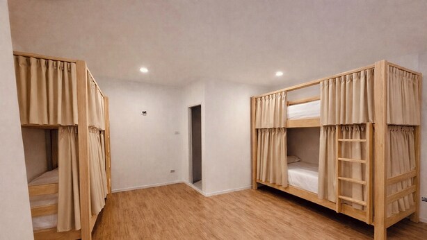 A room with two bunk beds, wooden flooring, and a door leading to another room. - Hostel 159 (Bangkok)