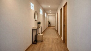 A hallway with a wooden floor, a mirror, a small table with a plant, and a basket. - Hostel 159 (Bangkok)