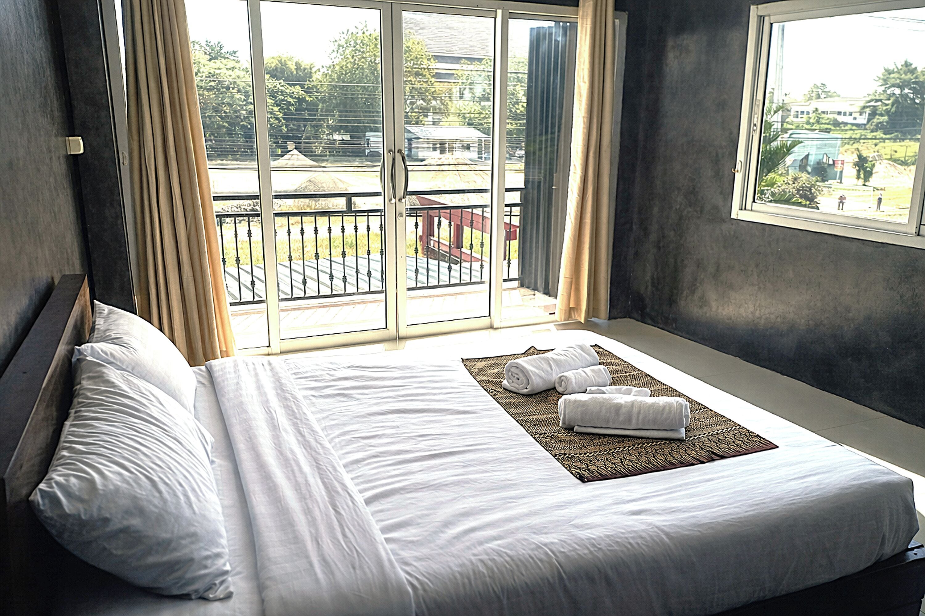 Una habitación de hotel con una cama grande, vistas a un balcón y una ventana.