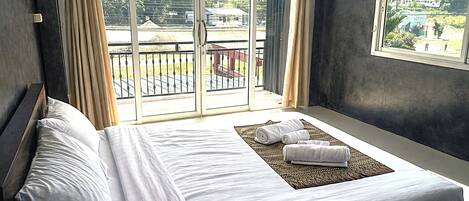 Una habitación de hotel con una cama grande, vistas a un balcón y una ventana.