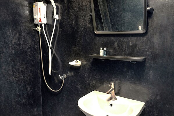 A bathroom with a white sink, a mirror, and a shower with a control panel. - B&T Hostel (Chiang Rai)