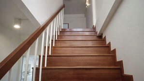 Un escalier en bois avec des rampes blanches et un luminaire fixé au plafond.