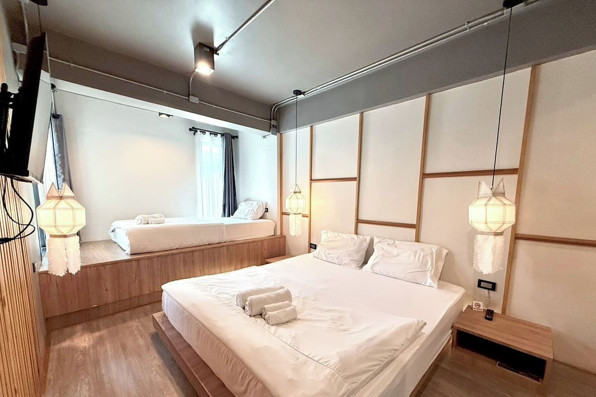 A modern hotel room with a large bed, a smaller bed, and a seating area with a view of the city.