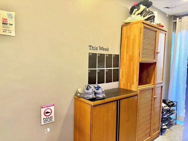 A room with a wooden cabinet, a shoe rack, and a calendar on the wall.
