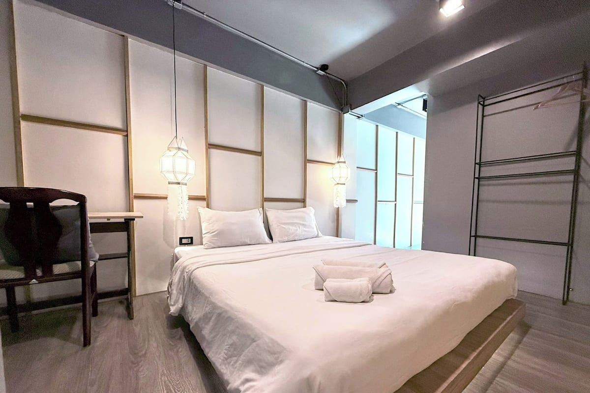 A modern hotel room with a large bed, a wooden chair, and a desk.