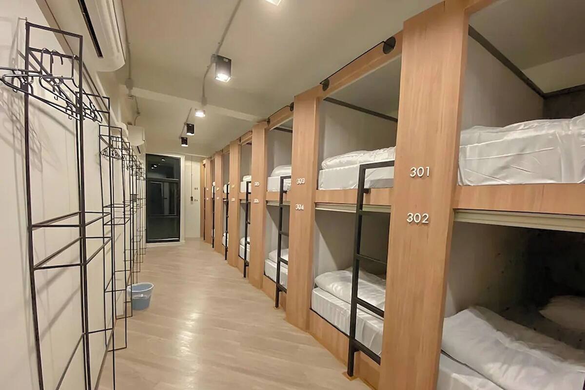 A corridor with bunk beds numbered 301 and 302, wooden lockers, and a metal rack system.