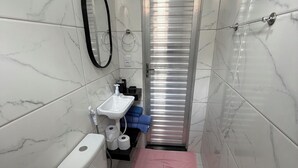 A compact bathroom with a toilet, sink, and shower area. - AmazHost - Blue house ideal for couples with Wi-Fi (Belém)