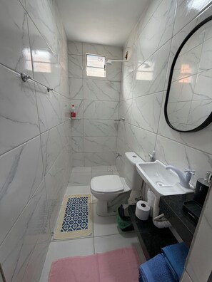 A small bathroom with white marble tiles, a toilet, a sink, and a mirror. - AmazHost - Blue house ideal for couples with Wi-Fi (Belém)