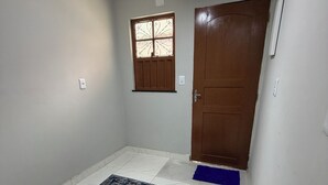 A hallway with a patterned rug, a wooden door, and a small window with decorative bars. - AmazHost - Blue house ideal for couples with Wi-Fi (Belém)