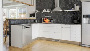 A modern kitchen with a black tiled backsplash, stainless steel appliances, and white cabinetry. - Skreanäs by Interhome (Falkenberg)