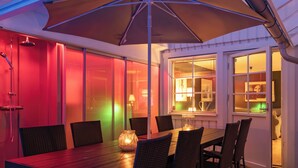 A dining area with a table and chairs, a large umbrella, and a view of the outside through a window. - Skreanäs by Interhome (Falkenberg)