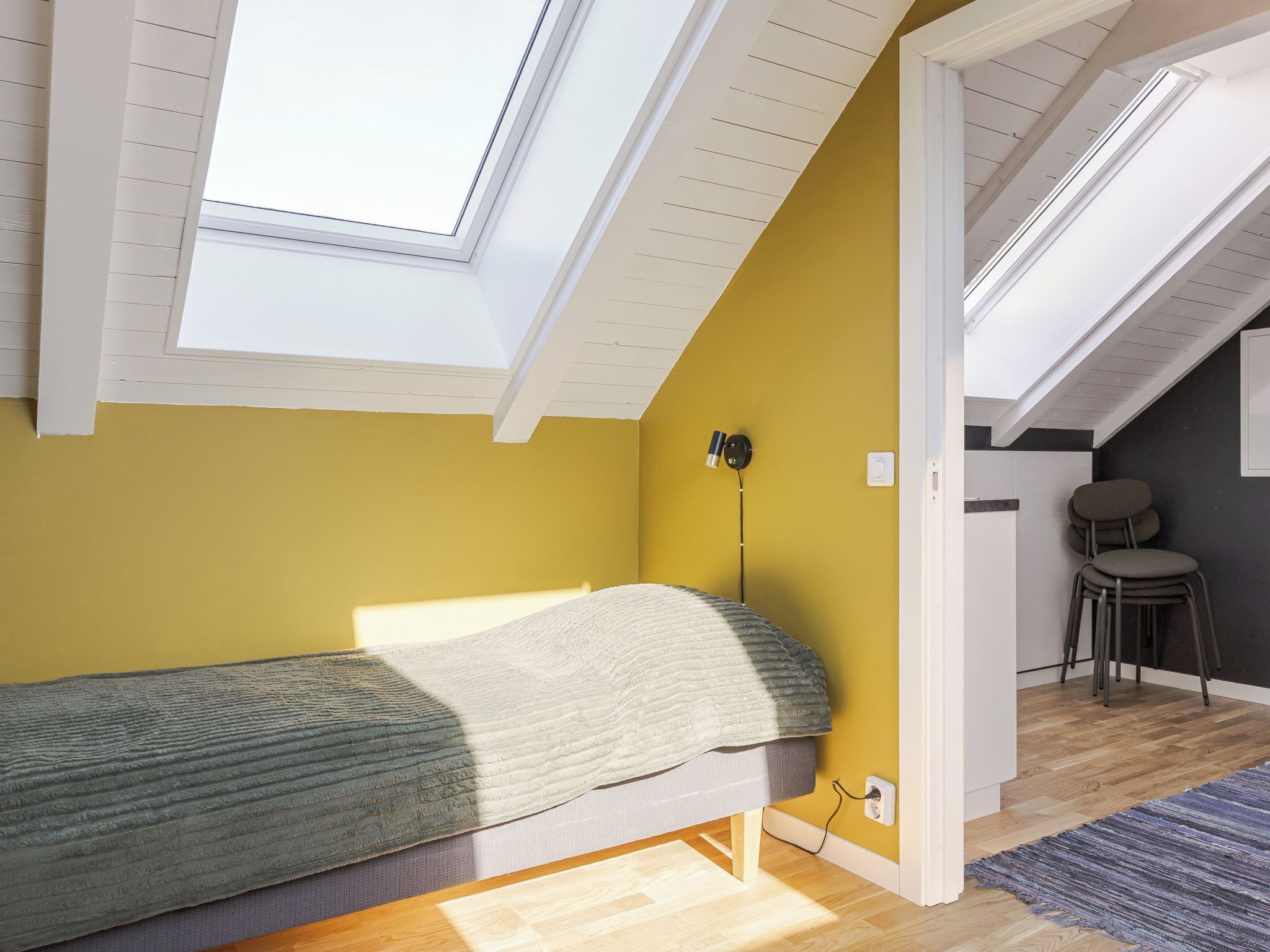 Une pièce comprenant un lit, un bureau, une chaise et une lucarne.
