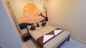 A bedroom with a bed, pillows, a nightstand, and a wall mural. - Sasirekha Residency & Homestay (Puducherry)