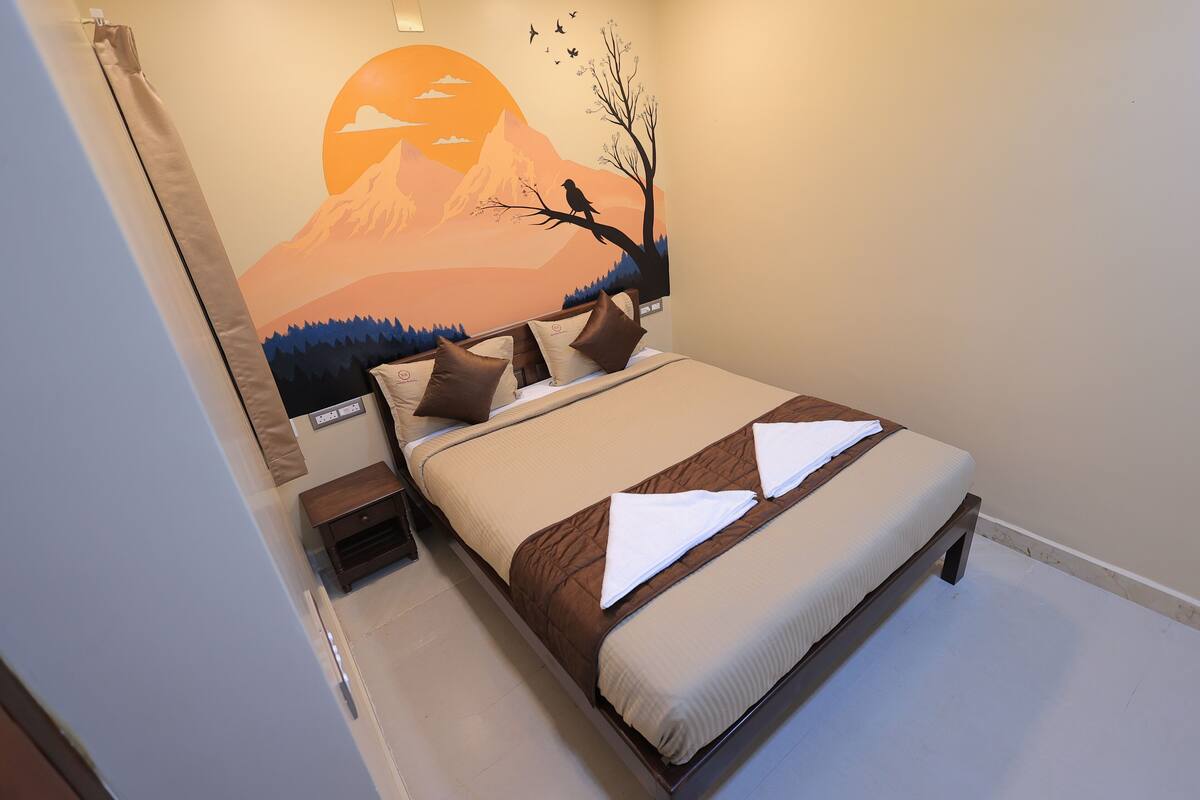 A bedroom with a bed, pillows, a nightstand, and a wall mural.