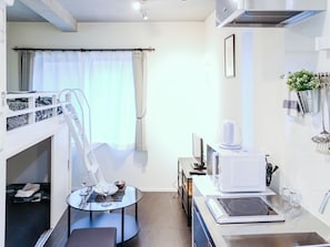 A compact hotel room with a bunk bed, a small dining table with a glass top, a microwave, a kettle, and a sink. - URBANAGE Takadanobaba (Tokyo)