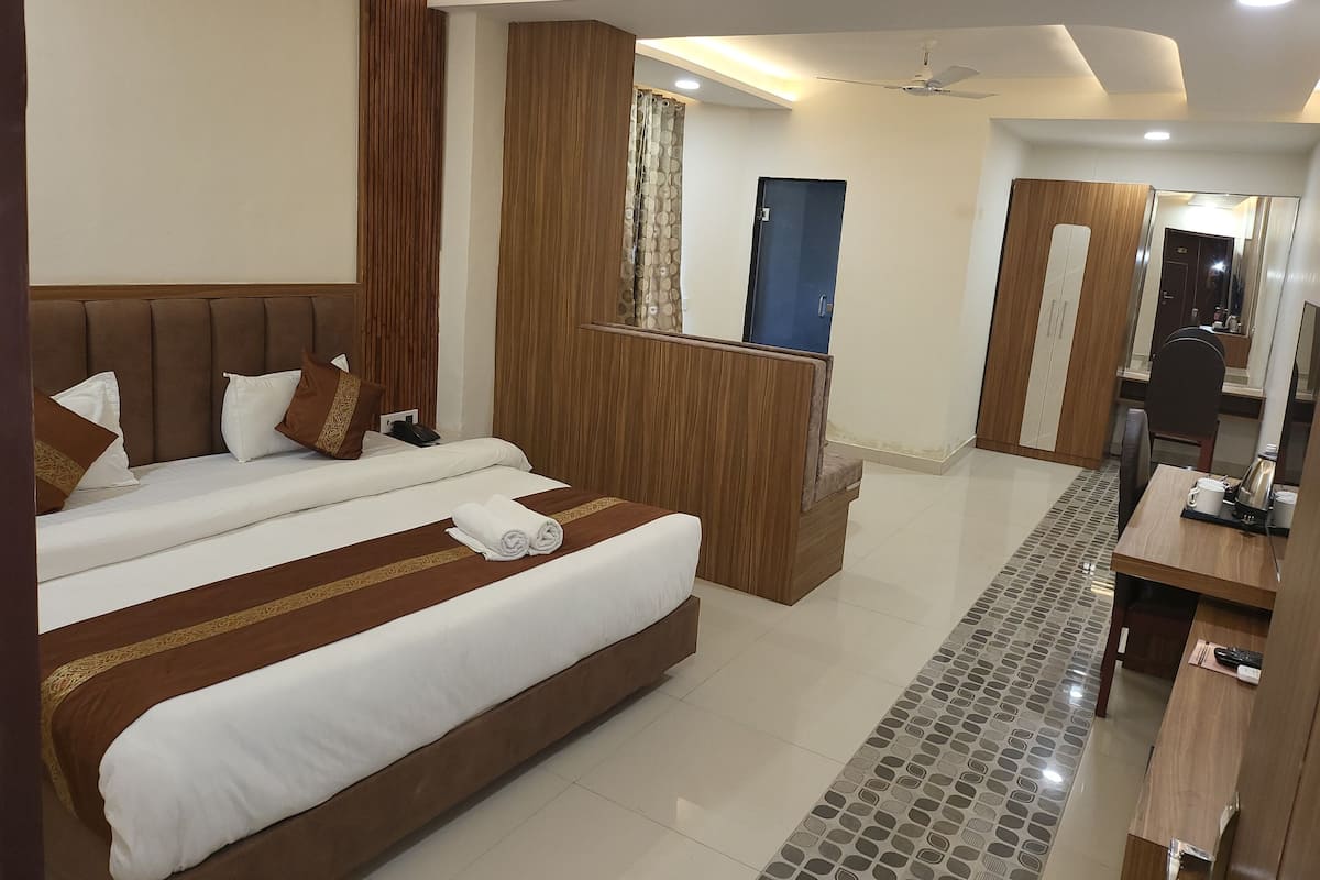 A modern hotel room with a large bed, a desk, a wardrobe, and a bathroom.