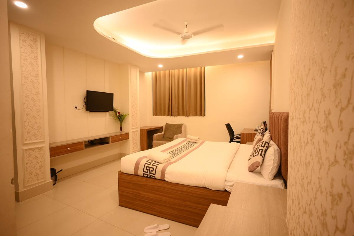A modern bedroom with a bed, a TV, a ceiling fan, and a nightstand.