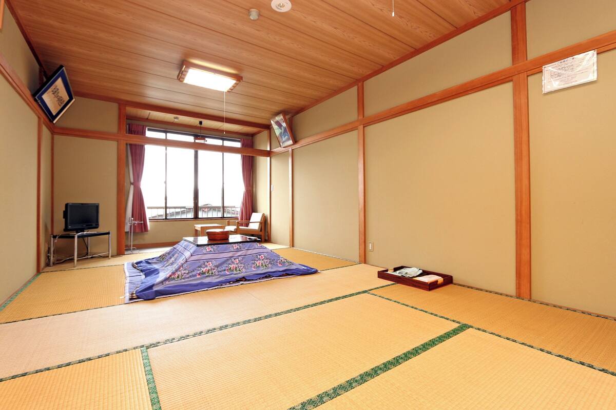 Een kamer met tatami matten, een televisie, een futon en een schuifdeur.