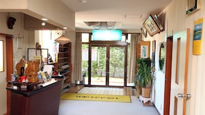 Un espace d’accueil comprenant un comptoir, un téléviseur, une grande fenêtre et une porte donnant sur l’extérieur.