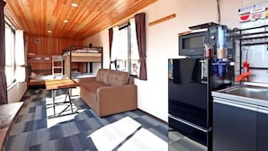Une petite cabine comprenant un coin cuisine, un canapé, une table à manger et un lit superposé.