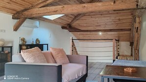 Ein gemütliches Zimmer mit Holzbalkendecke, einer Couch, einem Tisch und einem Bett.
