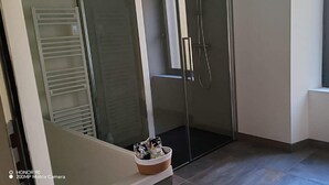 Ein modernes Badezimmer mit Duschkabine aus Glas, integriertem WC und einem Fenster für natürliches Licht.
