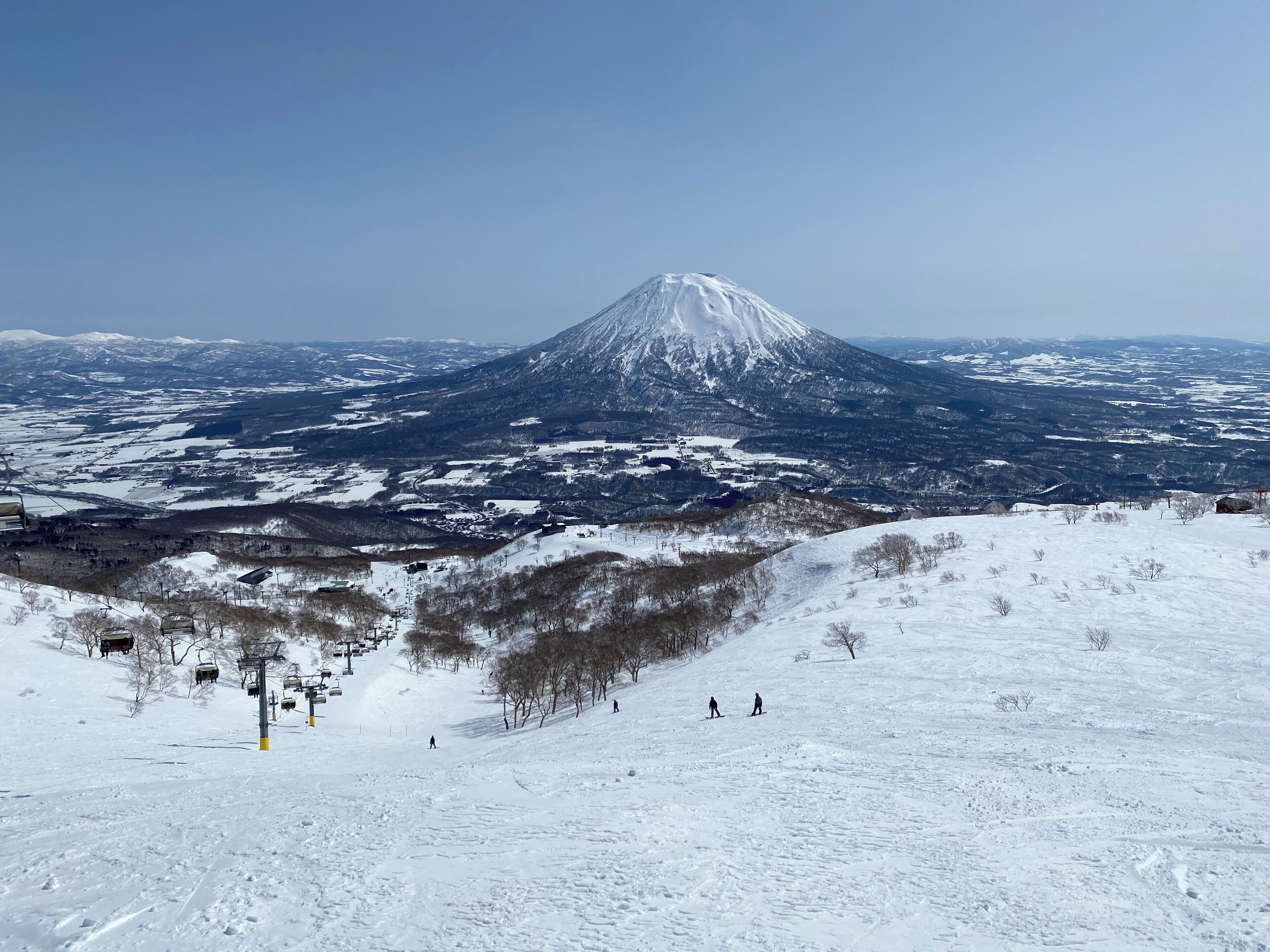 A snow-covered mountain with a ski lift and skiers.
