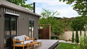 Een modern huis met een terras, een bank en een tafel met een fles en glazen.