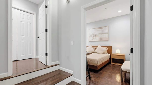 A bedroom with a bed, bedside table, and a nightstand. - Modern Apartment w/ Parking & Fast NYC PATH Access (Jersey City)