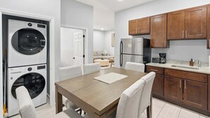 A compact kitchen with wooden cabinets, a refrigerator, and a built-in washing machine. - Modern Apartment w/ Parking & Fast NYC PATH Access (Jersey City)