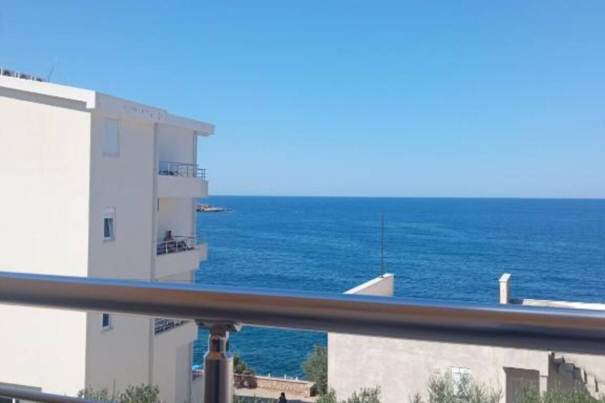 A white building with balconies overlooking the sea.