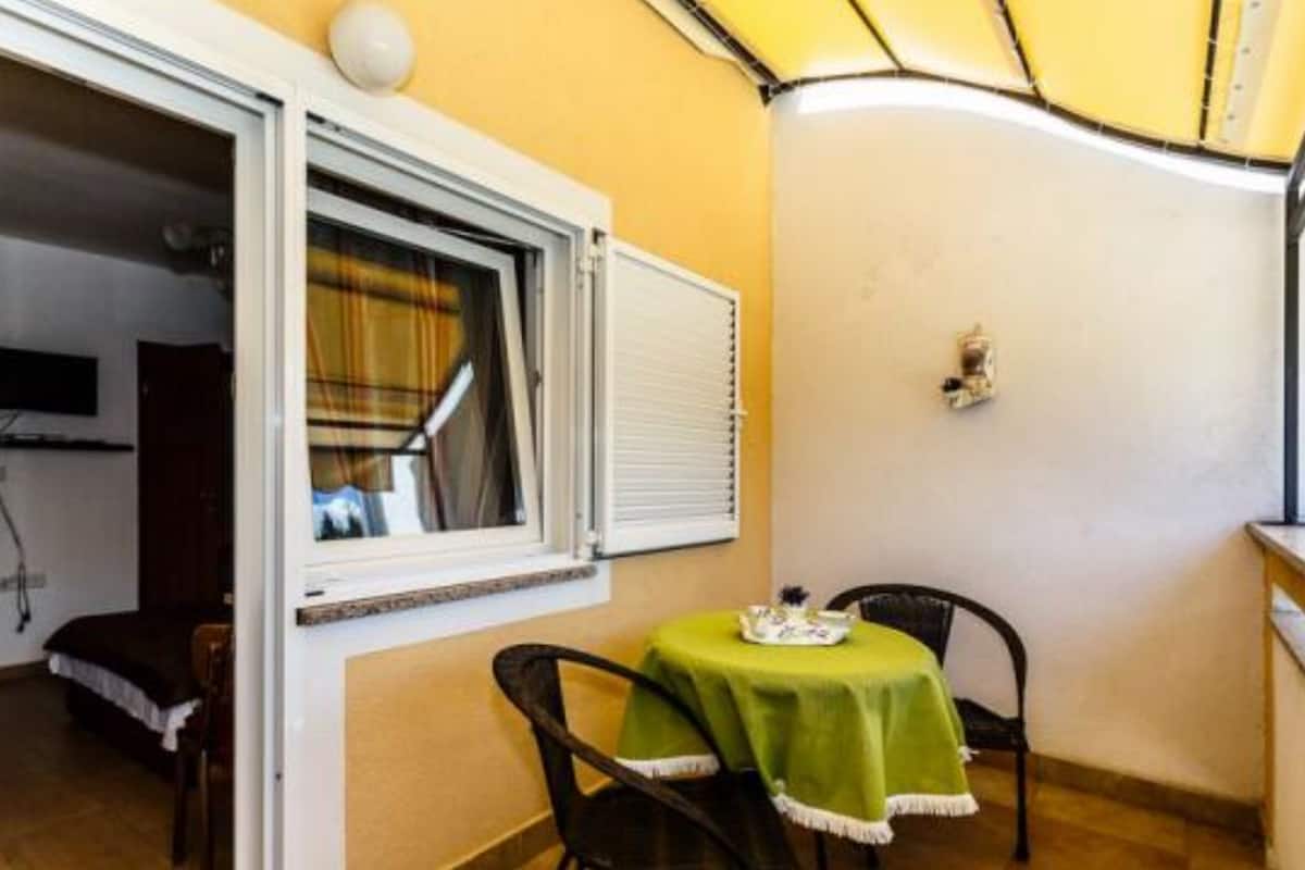 Una habitación pequeña con ventana, una mesa con mantel verde, dos sillas y un pequeño adorno en la pared.