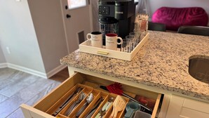 A kitchen with a coffee maker, mugs, and a drawer with utensils. - 3BR w/ Pool Table & Ping Pong - Near Snowden District, Landers Cnt & Outlet Mall (Southaven)
