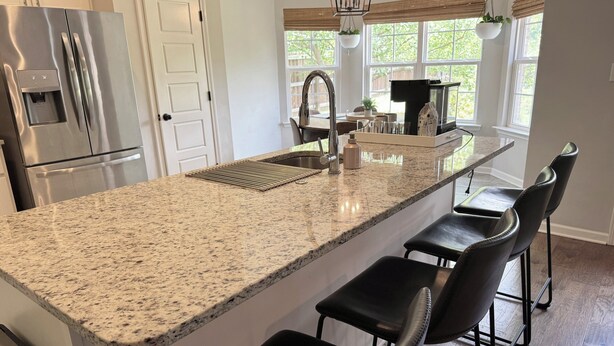 A kitchen with a granite countertop, stainless steel appliances, and a bar area with black chairs. - 3BR w/ Pool Table & Ping Pong - Near Snowden District, Landers Cnt & Outlet Mall (Southaven)