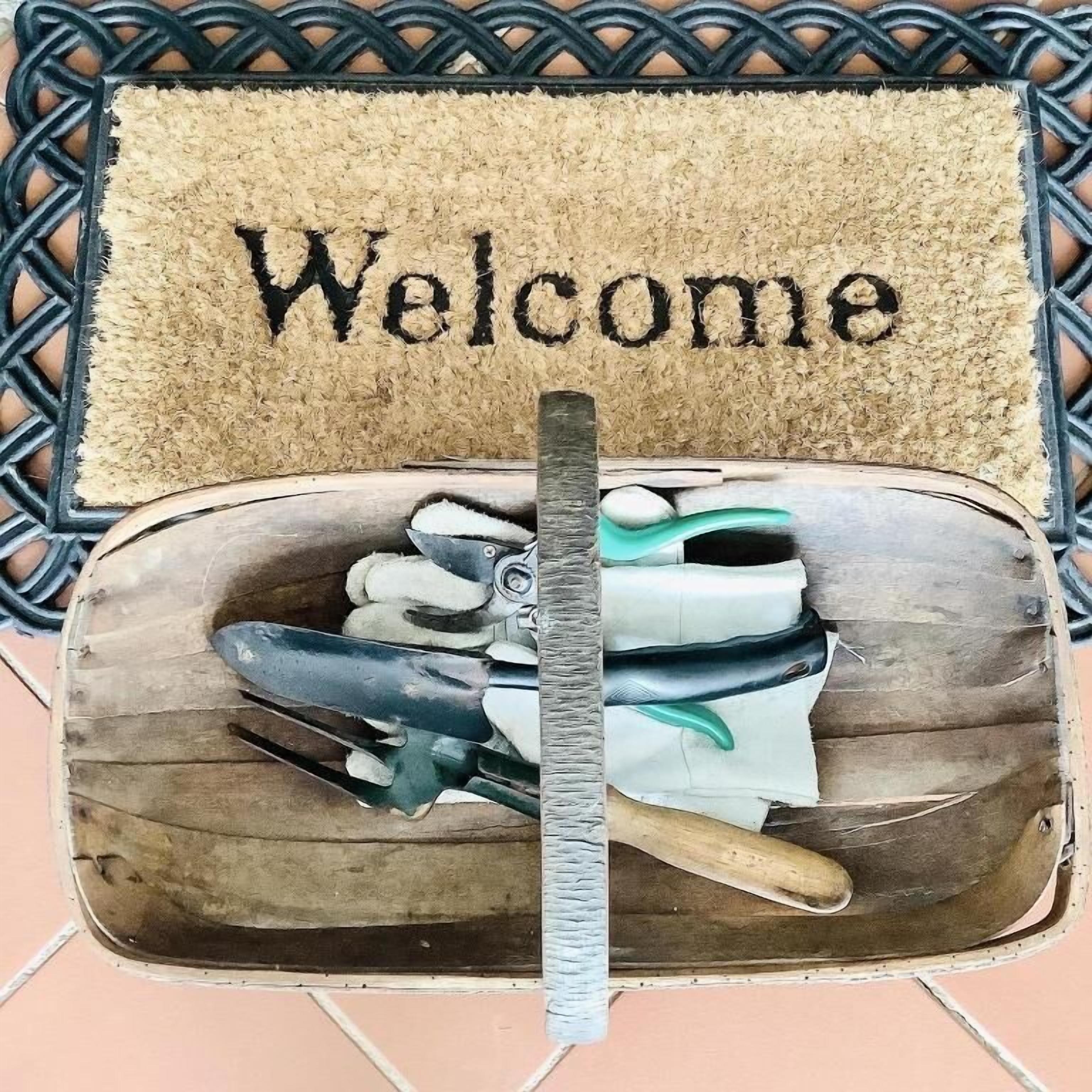 A welcome mat with the word "Welcome" and a wooden box containing gardening tools.