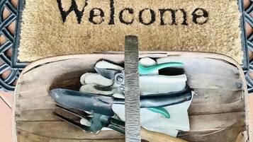 A welcome mat with the word "Welcome" and a wooden box containing gardening tools.