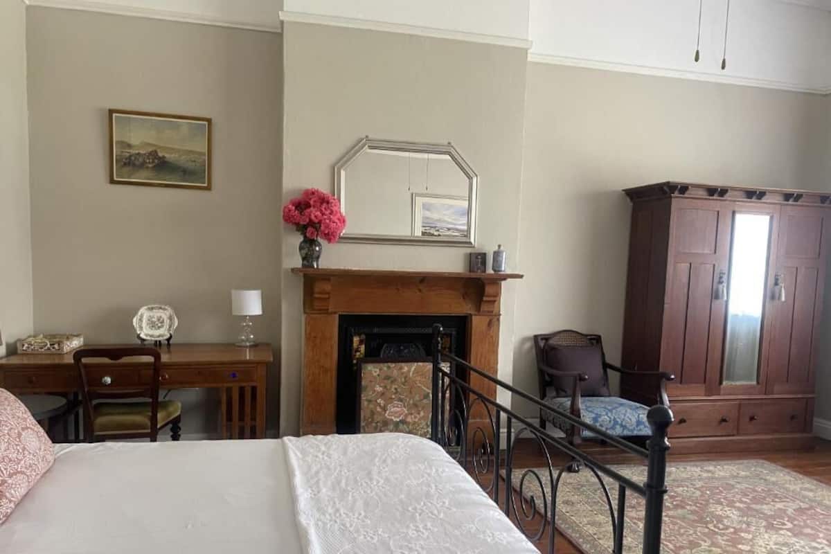 Un dormitorio con cama, escritorio, silla, chimenea y armario.