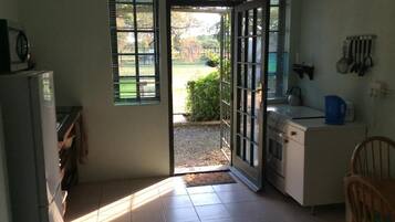 Tweepersoonskamer, terras, uitzicht op tuin | Privékeuken | Een microgolfoven, kookgerei, borden en bestek